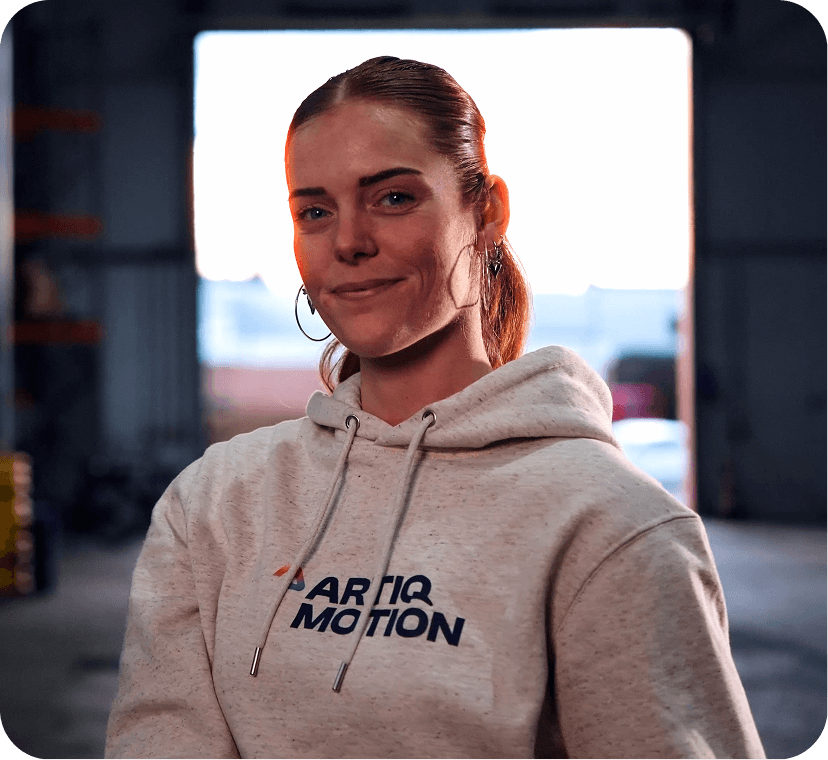 Lachende vrouw met Artiq Motion hoodie in industriële omgeving